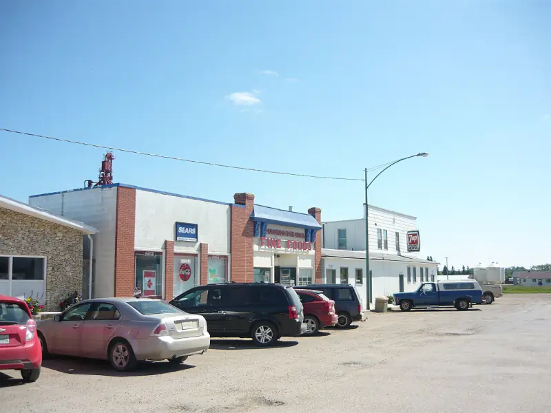 Bruno's main street with the Fine Foods grocery, the Bruno Hotel sign and trucks on the gravel street