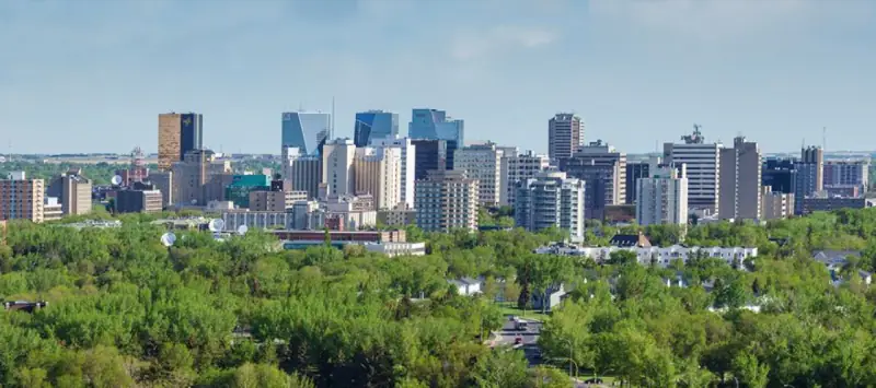 Downtown Regina skyline above a broad band of summer trees