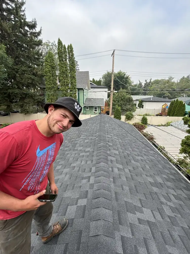 One of our crew on a finished asphalt shingle roof, ridge caps run out to the end, Saskatoon, SK