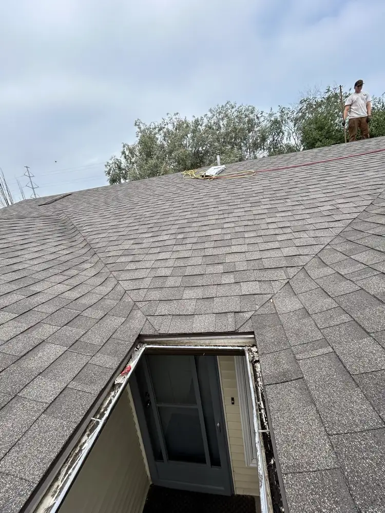A crew member up at the ridge partway through a re-roof, Saskatoon, SK, on the Home page