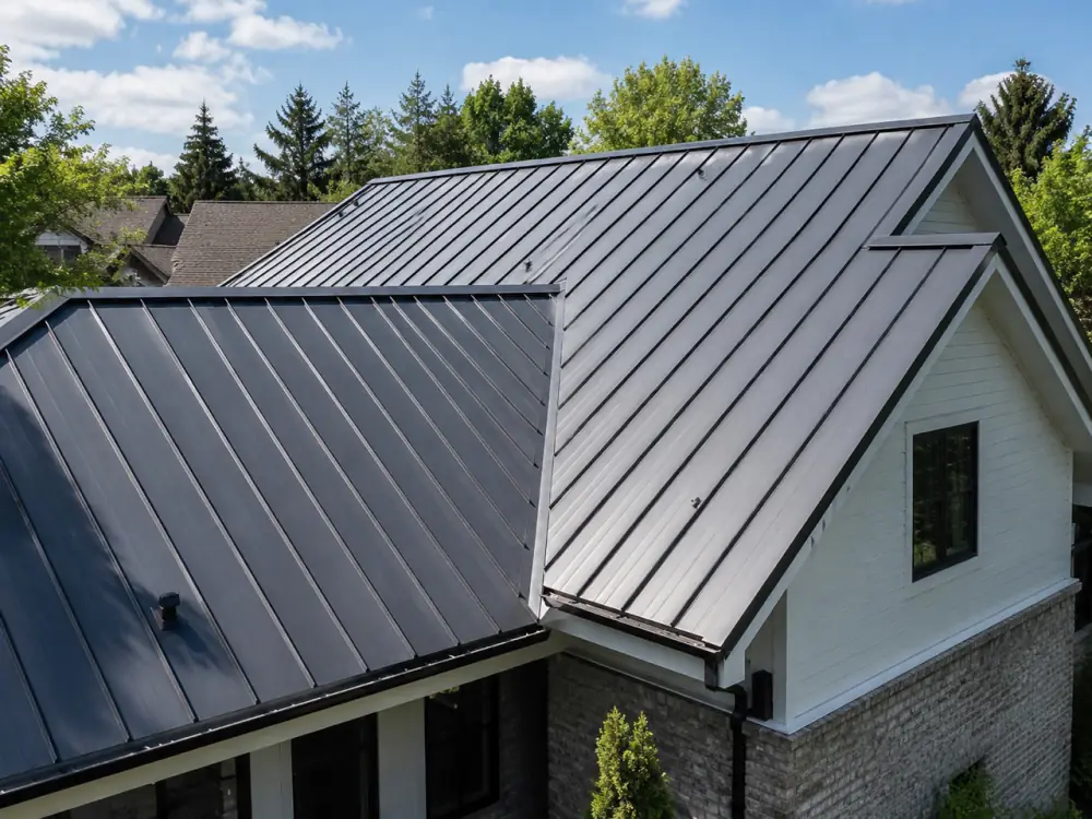Dark standing-seam metal roof across several gables of a two-storey house with white siding and brick